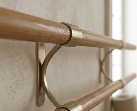 Hölzerne Ballettstange mit goldenen Haltern an der Wand